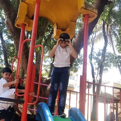 Vidyaramba students playing on outdoor play equipment during a field trip